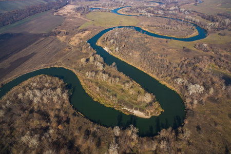 Early spring landscape with drone on meandering ribbon of river and trees without leavesの写真素材