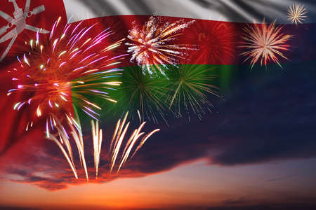 Majestic fireworks in evening sky and flag of Oman for Independence dayの写真素材
