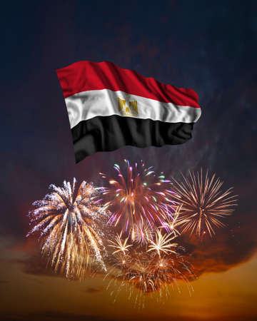 Holiday fireworks in evening sky and flag of Egypt for National Independence dayの写真素材