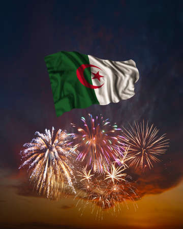 Holiday fireworks in evening sky and flag of Algeria for National Independence dayの写真素材