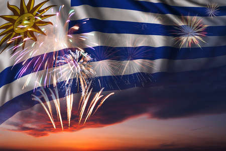 Majestic fireworks in evening sky and flag of Uruguay for Independence day or National Holidayの写真素材