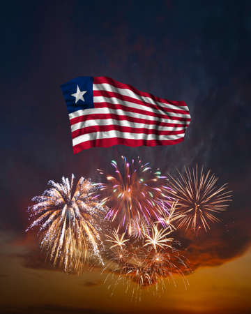 Holiday fireworks in evening sky and flag of Liberia for National Independence dayの写真素材