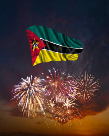 Holiday fireworks in evening sky and flag of Mozambique for National Independence dayの写真素材