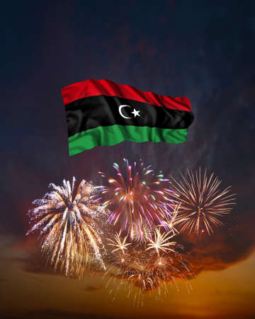 Holiday fireworks in evening sky and flag of Libya for National Independence dayの写真素材