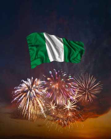 Holiday fireworks in evening sky and flag of Nigeria for National Independence dayの写真素材