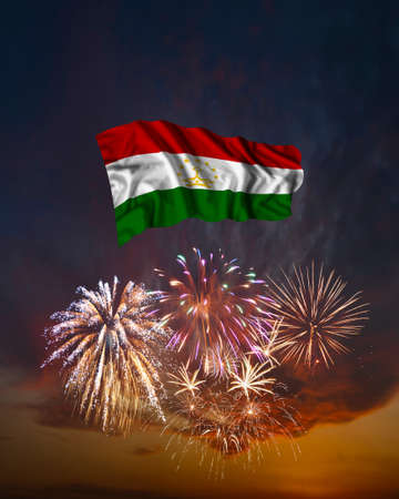 Holiday fireworks in evening sky and flag of Tajikistan for National Independence dayの写真素材