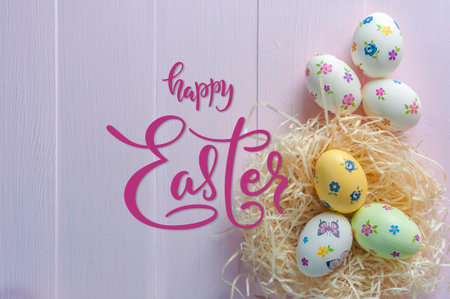 Hand lettering text Happy Easter and painted eggs on wooden colorful tableの写真素材