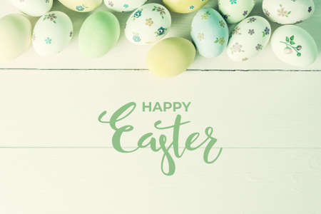 Easter painted eggs on wooden table and hand lettering text, retro film filter stylizationの写真素材