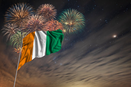 Waving National flag of Cote d Ivoire and holiday fireworks on night sky background with stars for independence dayの写真素材
