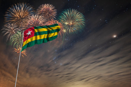 Waving National flag of Togo and holiday fireworks on night sky background with stars for independence dayの写真素材