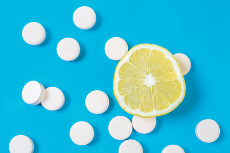 Close up of lemon and pills isolated on blue background. Top view. Cold prevention and treatment. Vitamin Cの写真素材