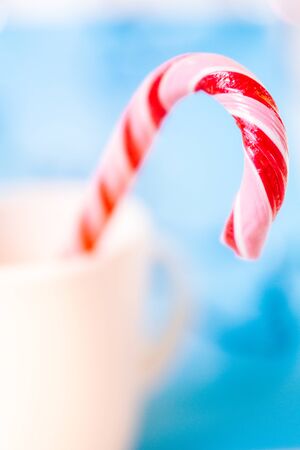 Christmas background. Caramel, bokeh, blur. Candy cane on blurred Christmas lights backgroundの写真素材