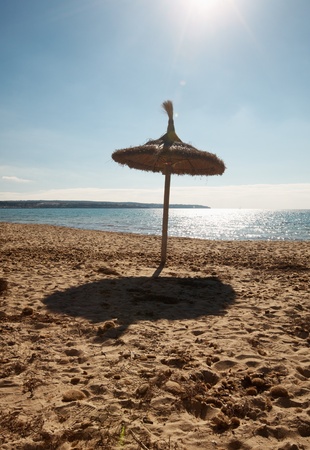 Empty beach with thatched beach umbrella, Majorca, Balearic Islands, Spainの写真素材