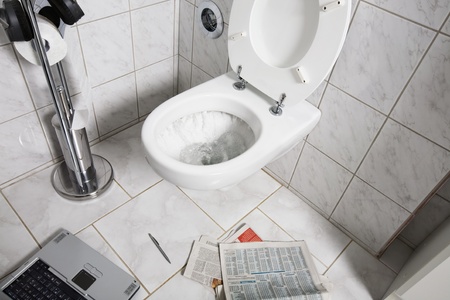 Newspaper, laptop and pen on floor by toiletの写真素材