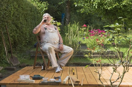 Senior enjoying beer in his gardenの写真素材