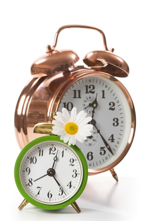 Two alarm clocks with daisy flower on whiteの写真素材