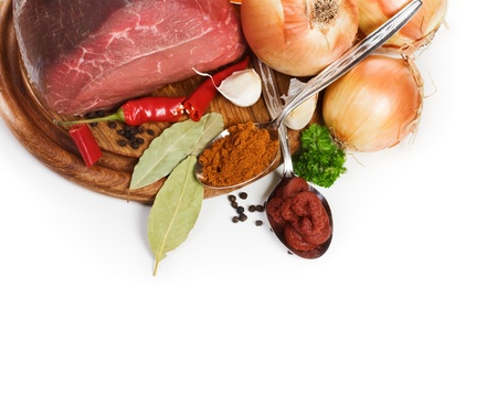 Meat and ingredients for goulash on chopping board, close-up, white backgroundの写真素材