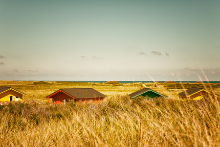 Colorful beach houses in dune grass at the beach of Helgoland, North sea, Germany. Travel destinations. Selective focus. Toned in warm colorsの写真素材