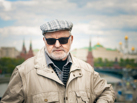 Portrait of old man in sunglasses and cap. Tourist in front of the Kremlin, Moscow. Travel destination.の写真素材