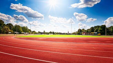 Red running track in stadium over blue sky with clouds in summertimeの写真素材