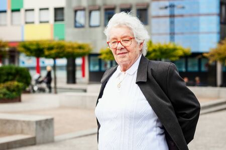 Cheerful smiling old woman walking in city