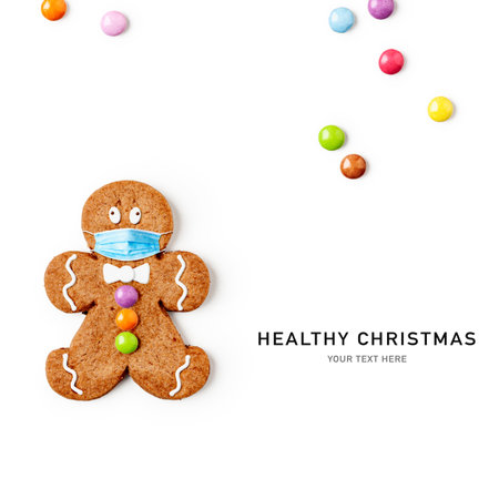 Gingerbread man with medical mask and candies isolated on white background. Pandemic christmas...