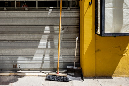 Broom and shovel in front of yellow wallの写真素材