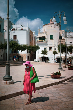 A woman with a covid19 protective mask walks in a street in summerのeditorial素材
