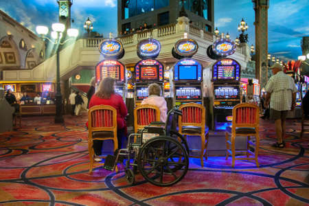 Two women with a wheelchair play slot machines in a casinoのeditorial素材