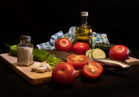 Traditional summer cold tomato soup gazpacho ingredients on a wood plank -Tomatoes, pepper, cucumber, garlic, salt and olive oil - black background - mediterranean, spanish food conceptの写真素材