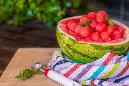 sweet and juicy watermelon small balls, served using the skin as a bowl over a wooden table. Summer food concept. Selective focusの写真素材