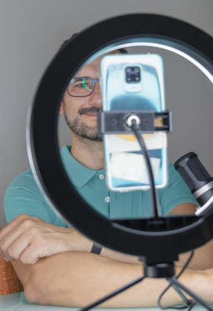 one man making a video call with his smart phone and a light ring studio lamp