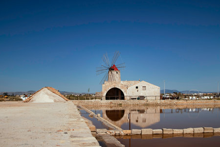 salt pans of Nubia, near Trapani and Marsalla (Sicilia, Italy) with one windmill in the backgroundの写真素材