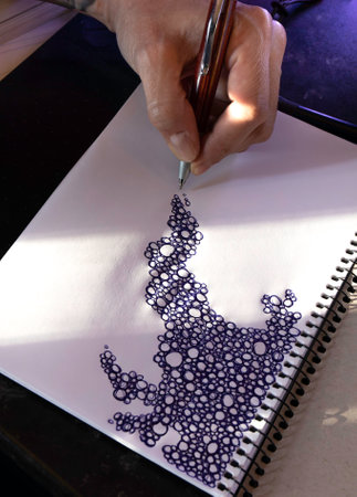 Close up of a hand drawing a pattern of scribbled bubbles on a blank scrapbook. Boredom, creativity conceptの写真素材