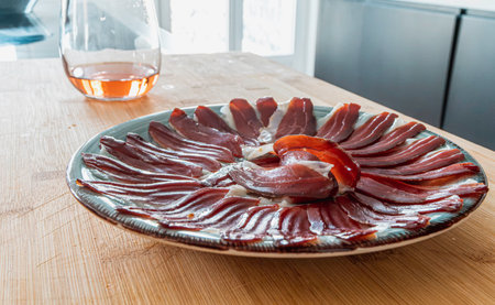 a plate of slices of iberic ham on a plate and a glass of wine on a table in the kitchen. Spanish traditional ham. selective focusの写真素材