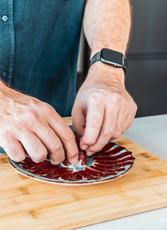 One man serving slices of iberic ham on a plate. Spanish traditional hamの写真素材