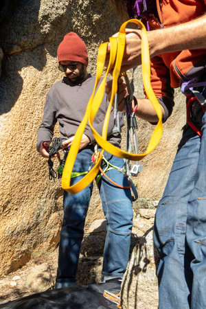 two young adults preparing climbing equipment in the mountains during a sunny winter dayの写真素材