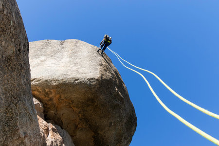 Young adult rock climber rappelling a granite wall in Torrelodones, Madrid. Extreme sports conceptの写真素材