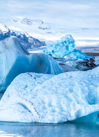 A large block of ice is surrounded by smaller blocks of ice. The scene is serene and peaceful, with...