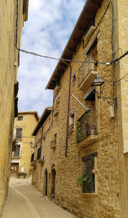 A narrow alleyway with a building on the left and another building on the right. The buildings are made of stone and have balconiesの写真素材