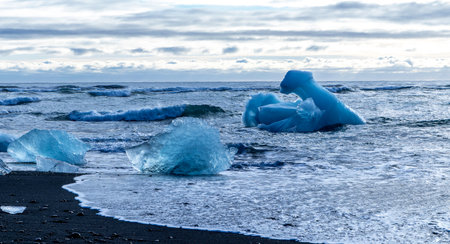 A body of water with a large chunk of ice floating on top. The ice is surrounded by smaller pieces of ice, creating a beautiful and serene sceneの写真素材