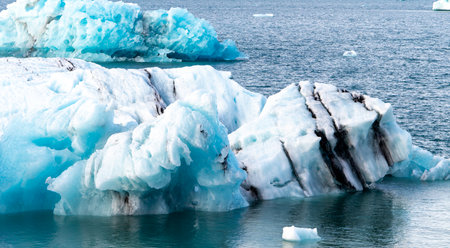 A large block of ice is floating in the ocean. The ice is surrounded by water and has a blue tint to itの写真素材