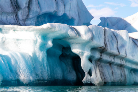 A large ice block with a blue hole in it. The hole is surrounded by ice and forms a tunnelの写真素材