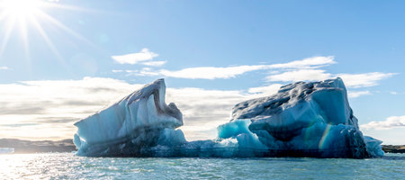 A large ice block is floating in the ocean. The sun is shining on the ice, creating a beautiful and serene sceneの写真素材