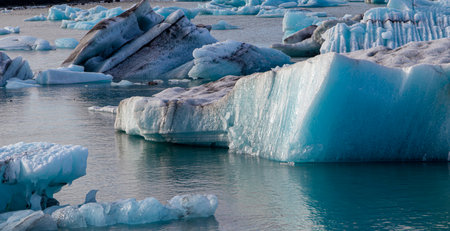 A large chunk of ice is floating in the ocean. The water is blue and the ice is whiteの写真素材