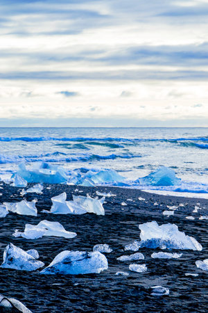 The ice is scattered all over the beach, and the person is looking out at the ocean