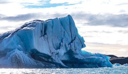 A large ice block. The ice is blue and the sky is cloudy
