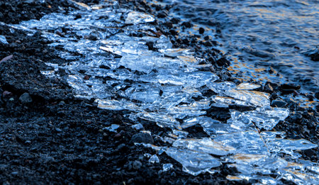 A large pile of broken ice crystals on a beach. The ice is melting. Scene is cold and desolate