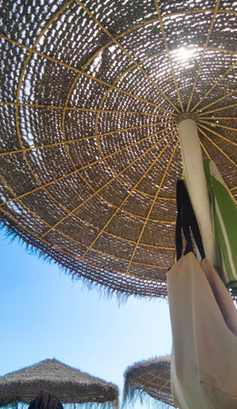 A large umbrella at the beach on a sunny day with a bag hanging from it. vacations in paradiseの写真素材