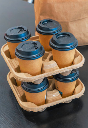 A stack of coffee cups with lids on top of each other. The cups are in a paper tray, ready to take awayの写真素材